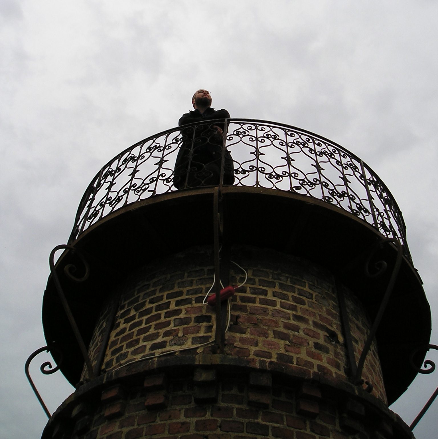 Person schaut von Turm mit Gitterbrüstung herunter
